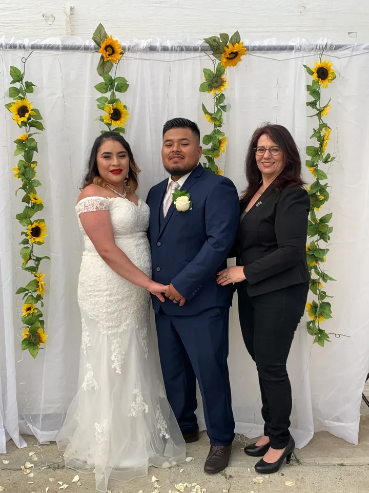 bride and groom smiling with wedding officiant